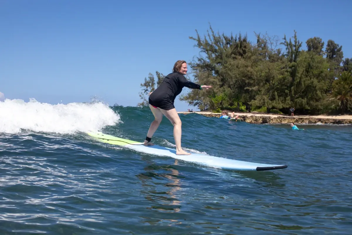 Hawaii surf student practices riding waves, North Shore Oahu Surf School. Learn to surf in Hawaii, book a lesson now.